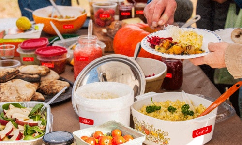 Outdoor family reunion potluch spread with BBQ, potato salad, chicken and beverages.